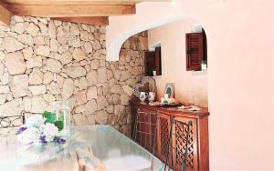 Cette chambre dispose d'une table en verre et d'un mur en pierre. dans l'établissement Monica Luxury House, à Porto Cervo
