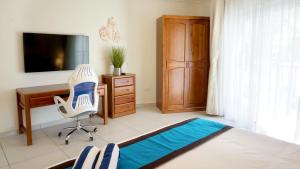 Arena Condominium Aruba في شاطئ بالم إيغل: غرفة نوم بها مكتب وكرسي وتلفزيون