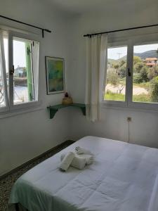 a bedroom with a white bed with two windows at House Kokkalas on the beach in Pyrgadikia