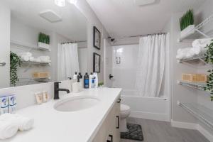 een witte badkamer met een wastafel en een bad bij Your Perfect 2BR Stay in SE Calgary in Calgary