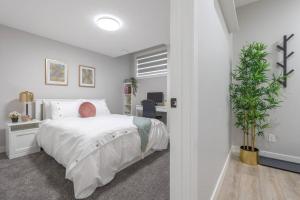 een slaapkamer met een wit bed en een potplant bij Your Perfect 2BR Stay in SE Calgary in Calgary