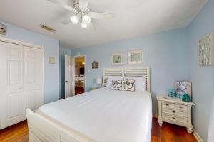 Schlafzimmer mit einem weißen Bett und einem Deckenventilator in der Unterkunft Captain's Quarters in Galveston