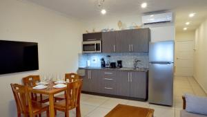 a kitchen with a table and a stainless steel refrigerator at Arena Condominium Aruba in Palm-Eagle Beach