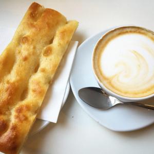 un piatto con una tazza di caffè e un pezzo di pane di Approdo 36 a La Spezia