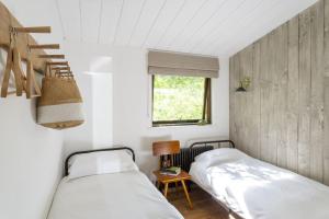 2 łóżka w małym pokoju z oknem w obiekcie Den in the Woods w mieście Slapton