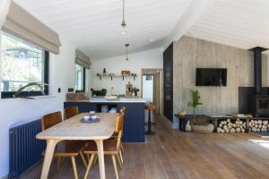 a kitchen and living room with a wooden table and chairs at Den in the Woods in Slapton