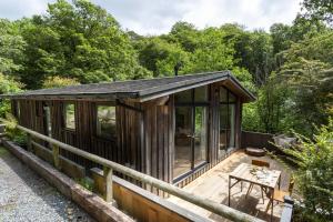 a cabin in the woods with a wooden deck at Den in the Woods in Slapton