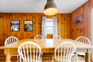 uma sala de jantar com uma mesa de madeira e cadeiras brancas em Rockhouse Mountain Retreat em Conway