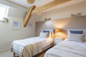 two beds in a bedroom with a vaulted ceiling at East Cornworthy Barton in Totnes