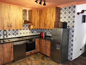 La cuisine est équipée d'armoires en bois et d'un réfrigérateur en acier inoxydable. dans l'établissement Aladin Comfort Country House, à Campinho