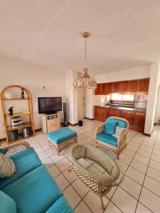 sala de estar con sofá azul y sillas en 2 Bedroom 2 bathroom condo pool, tennis beach club, en Manzanillo