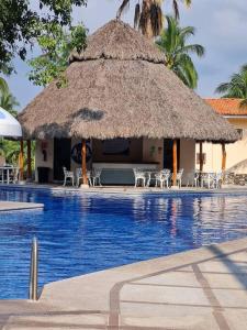 una gran piscina con sombrilla y sillas de paja en 2 Bedroom 2 bathroom condo pool, tennis beach club, en Manzanillo