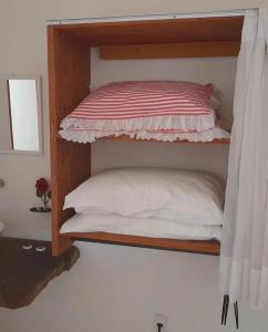 a wooden bunk bed with a white pillow on it at Pousada Vila Sol Maior in Guarapari +115 photos