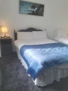 a bedroom with a bed with a blue blanket on it at Ostán Oileán Thoraí Tory Island Hotel in Tory Island