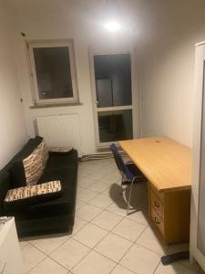 sala de estar con sofá, escritorio y silla en Fałata apartament, en Kobyłka