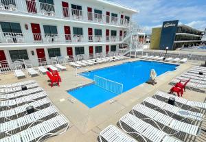 a hotel with a swimming pool and chairs and a building at Cardinal Motel in North Wildwood