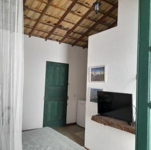 a room with a green door and a television at Pousada Vila Sol Maior in Guarapari