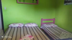 two beds in a room with a green wall at Flats quase beira mar ar piscinas até 8 pessoas caseiro in Itamaracá +21 photos
