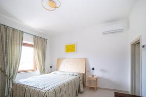 una camera da letto bianca con un letto e una finestra di La Casa degli Dei a San Gimignano