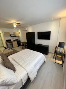 a bedroom with a large white bed and a living room at Suites By SalcedO in Santo Domingo