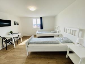 a white bedroom with two beds and a desk at Monteurzimmer ZIMMERzuVERMIETEN in Lengnau BE in Lengnau