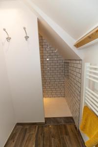 a walk in shower in a bathroom with white walls and wood floors at Le paille en queue in Sainte-Mère-Église