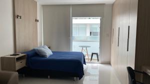 - une chambre avec un lit bleu et une porte donnant sur un balcon dans l'établissement Monoambiente en Condominio Zero, à Santa Cruz de la Sierra