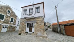 a white house with a balcony on a street at Casa de Ade in Monte da Velha