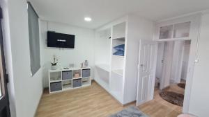 a white living room with a tv on a wall at Casa de Ade in Monte da Velha