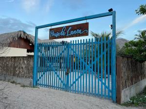 une porte bleue devant un bâtiment avec un panneau dans l'établissement Pousada Lanea Experience, à Atins