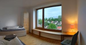 Zimmer mit einem großen Fenster, einem Bett und einem Schreibtisch in der Unterkunft Kubus 28A in Gräfenberg