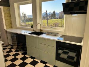 a kitchen with a sink and two windows with a view at Rødseth gårdsovernatting Dobbeltrom in Molde