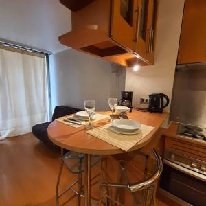 a small kitchen with a table with two wine glasses at Departamento con excelente ubicación cerca metro los Leones in Santiago