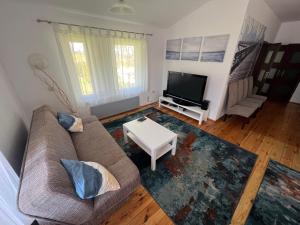 a living room with a couch and a tv at Domek Przy Plaży in Gąski