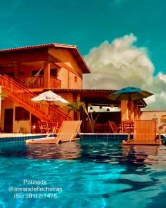 a resort with a swimming pool with chairs and umbrellas at Pousada Areias de Flecheiras in Flecheiras