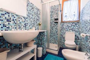 een blauw betegelde badkamer met een wastafel en een toilet bij Piccapiana Sea View Attic Flat in La Spezia +26 foto's