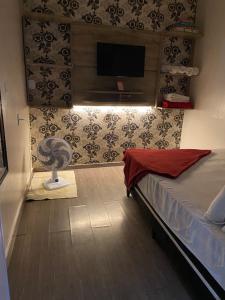 - une chambre avec un lit et une télévision à écran plat dans l'établissement Suite cantinho do sossego, à Arraial do Cabo