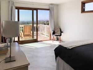 a bedroom with a bed and a balcony with a chair at Malibu Seaside Bliss with Hot Tub and Beach & Hike nearby in Malibu