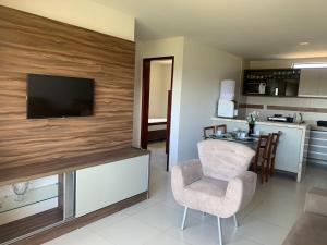 uma sala de estar com uma televisão, uma cadeira e uma mesa em Cond. Sonhos da Serra em Bananeiras