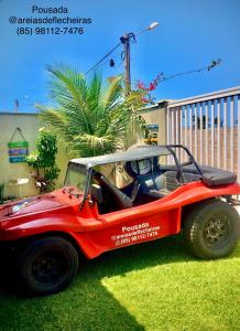 czerwony samochód czterokołowy zaparkowany na trawie w obiekcie Pousada Areias de Flecheiras w mieście Flecheiras