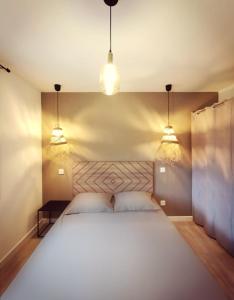 a bedroom with a large white bed with two lights at KiWi in Canet-en-Roussillon