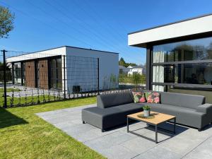 a patio with a couch and a table at Edelhert, moderne en comfortabele vakantiewoning met hottub! in Ermelo