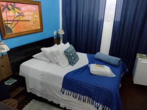 1 dormitorio con 1 cama con paredes azules y cortinas azules en Pousada Vila Inconfidentes - Centro Historico, en Tiradentes