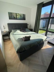 een bed in een slaapkamer met een groot raam bij Edelhert, moderne en comfortabele vakantiewoning met hottub! in Ermelo