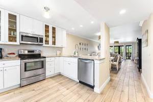 una cocina con armarios blancos y electrodomésticos de acero inoxidable en Stay Siesta Dunes en Siesta Key