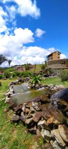 a creek with rocks and a building in the background at Cond. Sonhos da Serra in Bananeiras