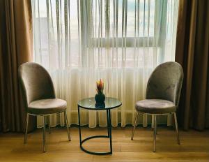 two chairs and a table and a vase with flowers on it at Skymoon Istanbul Airport Hotel in Arnavutköy