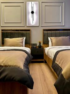 a bedroom with two beds and a nightstand between them at Skymoon Airport Hotel in Arnavutköy