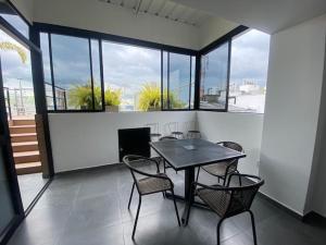 una mesa y sillas en una habitación con ventanas en Cómodo Apartaestudio Norte AXM en Armenia