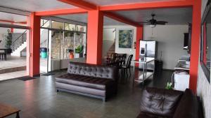 a living room with a leather couch and a kitchen at Quinta Sunset, Lago de Coatepeque in El Congo